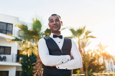 Kamera için poz vermek. Resmi kıyafetli zenci garson güneşli bir günde iş yerinde..