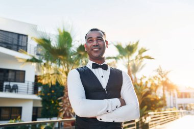 Kamera için poz vermek. Resmi kıyafetli zenci garson güneşli bir günde iş yerinde..