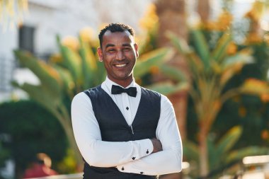 Kamera için poz vermek. Resmi kıyafetli zenci garson güneşli bir günde iş yerinde..