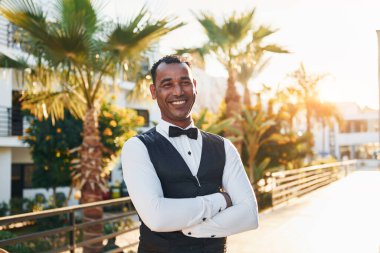 Kamera için poz vermek. Resmi kıyafetli zenci garson güneşli bir günde iş yerinde..