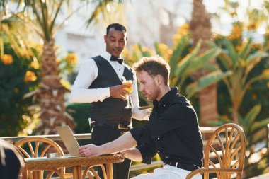 Garson tarafından servis ediliyor. Genç adam güneşli bir günde dışarıda. Tatil kavramı.