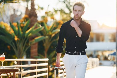 Seyahat çantasıyla. Genç adam güneşli bir günde dışarıda. Tatil kavramı.