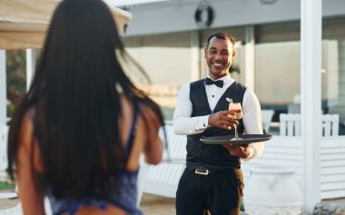 Kadın siparişi. Resmi kıyafetli zenci garson güneşli bir günde iş yerinde..