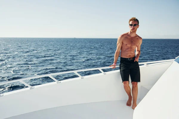 Güneş gözlüklü. Genç erkek turist denizdeki yatta. Tatil kavramı.