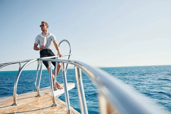 Kamera için poz vermek. Genç erkek turist denizdeki yatta. Tatil kavramı.