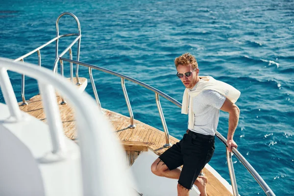 Kamera için poz vermek. Genç erkek turist denizdeki yatta. Tatil kavramı.