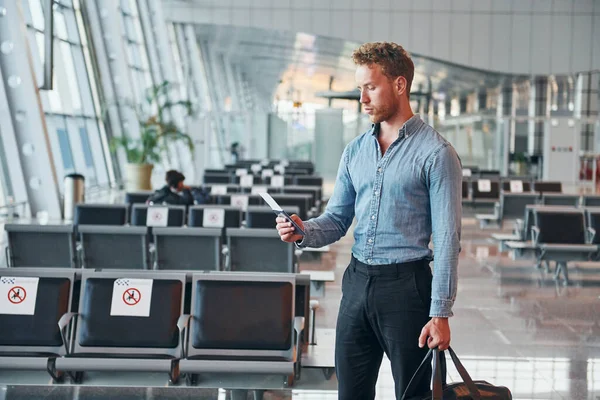 Resmi kıyafetli genç adam modern havaalanında. Tatil kavramı.