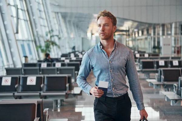 Resmi kıyafetli genç adam modern havaalanında. Tatil kavramı.