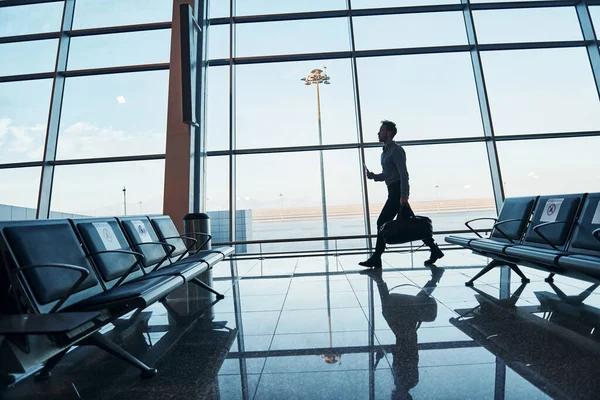 Young man in formal wear is in modern airport. Conception of vacation.