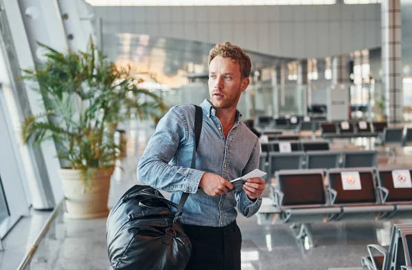 Resmi kıyafetli genç adam modern havaalanında. Tatil kavramı.