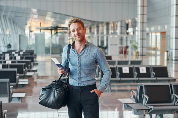 Resmi kıyafetli genç adam modern havaalanında. Tatil kavramı.