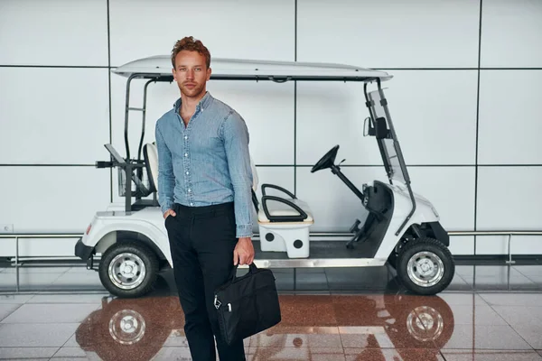 Araca karşı. Resmi kıyafetli genç adam modern havaalanında. Tatil kavramı.