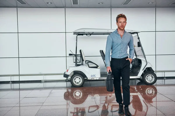 Araca karşı. Resmi kıyafetli genç adam modern havaalanında. Tatil kavramı.