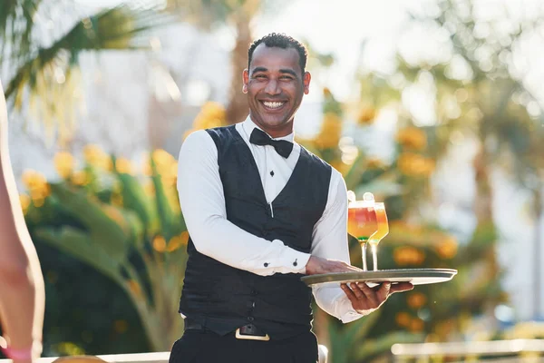 Kadın siparişi. Resmi kıyafetli zenci garson güneşli bir günde iş yerinde..