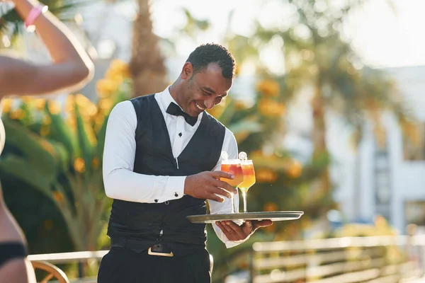 Kadın siparişi. Resmi kıyafetli zenci garson güneşli bir günde iş yerinde..