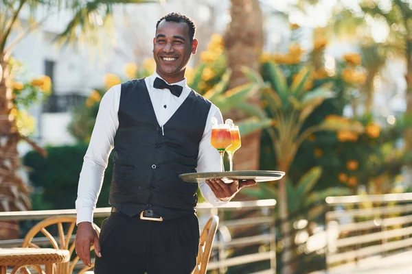 Resmi kıyafetli zenci garson güneşli bir günde iş yerinde..