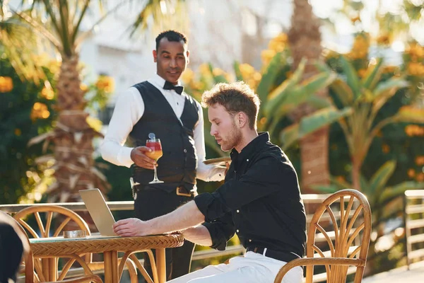 Garson tarafından servis ediliyor. Genç adam güneşli bir günde dışarıda. Tatil kavramı.