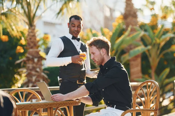 Garson tarafından servis ediliyor. Genç adam güneşli bir günde dışarıda. Tatil kavramı.