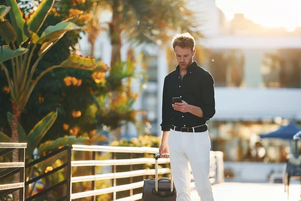 Seyahat çantasıyla. Genç adam güneşli bir günde dışarıda. Tatil kavramı.