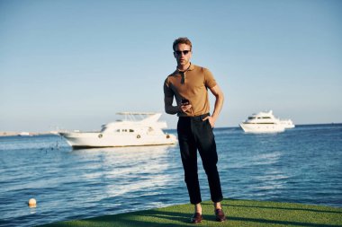 Güneş gözlüklü. Genç adam güneşli bir günde dışarıda. Tatil kavramı.