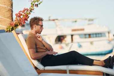 Parlak güneş ışığı. Genç adam güneşli bir günde dışarıda. Tatil kavramı.