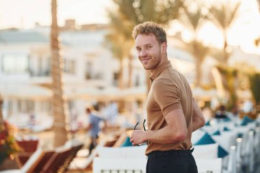 Parlak güneş ışığı. Genç adam güneşli bir günde dışarıda. Tatil kavramı.