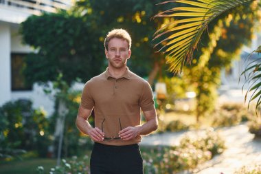 Parlak güneş ışığı. Genç adam güneşli bir günde dışarıda. Tatil kavramı.