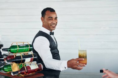 Elinde bir düzenle. Resmi kıyafetli zenci garson güneşli bir günde iş yerinde..