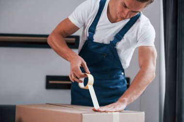 Kutuyu paketliyorum. Mavi üniformalı genç adam içeride çalışıyor..