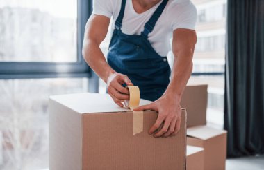 Kutuyu paketliyorum. Mavi üniformalı genç adam içeride çalışıyor..