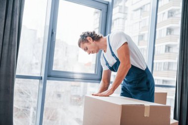 Kutuyu paketliyorum. Mavi üniformalı genç adam içeride çalışıyor..