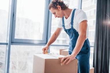 Kutuyu paketliyorum. Mavi üniformalı genç adam içeride çalışıyor..