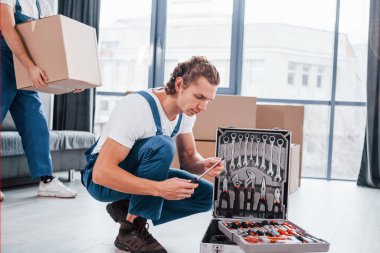 Davadaki aletleri kullanıyor. İçeride çalışan mavi üniformalı iki genç nakliyeci..