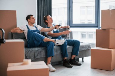 Kanepede oturuyordum. Yorgun ve dinleniyor. İçeride çalışan mavi üniformalı iki genç nakliyeci..