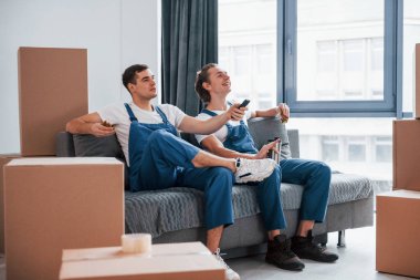 Kanepede oturuyordum. Yorgun ve dinleniyor. İçeride çalışan mavi üniformalı iki genç nakliyeci..