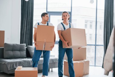 Yoğun bir gün. İçeride çalışan mavi üniformalı iki genç nakliyeci..