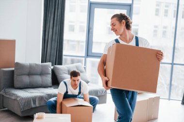 Ağır kutular. İçeride çalışan mavi üniformalı iki genç nakliyeci..