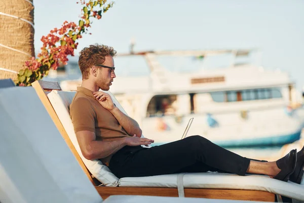 Parlak güneş ışığı. Genç adam güneşli bir günde dışarıda. Tatil kavramı.