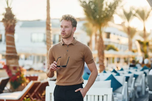 Parlak güneş ışığı. Genç adam güneşli bir günde dışarıda. Tatil kavramı.