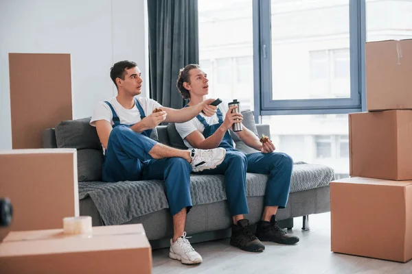 Kanepede oturuyordum. Yorgun ve dinleniyor. İçeride çalışan mavi üniformalı iki genç nakliyeci..