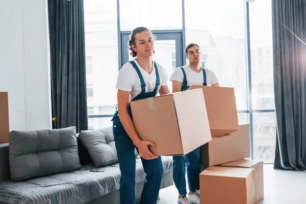 Yoğun bir gün. İçeride çalışan mavi üniformalı iki genç nakliyeci..