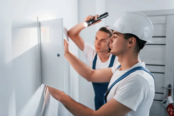 Two Young Male Electricians Works Indoors Together Using Flashlight — Zdjęcie stockowe