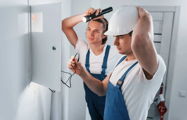 Two Young Male Electricians Works Indoors Together Using Flashlight — Zdjęcie stockowe