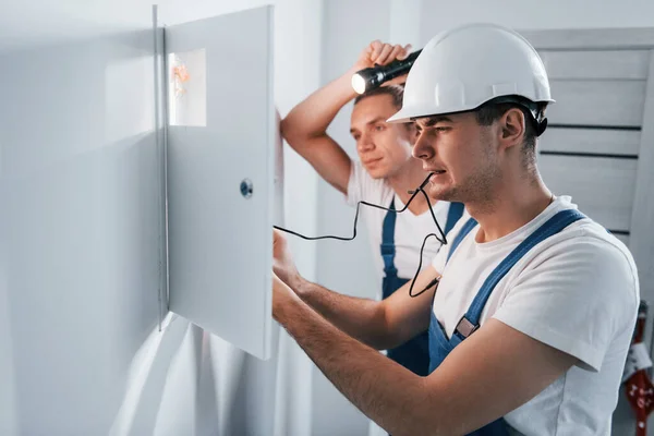 Twee Jonge Mannelijke Elektriciens Werken Binnen Samen Gebruik Van Zaklamp — Stockfoto