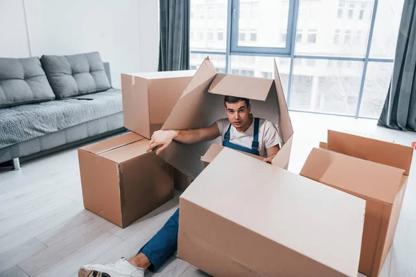 Mavi üniformalı genç erkek taşıyıcı kutularla yerde yatıyor..