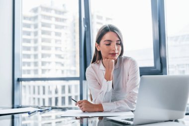 Beyaz elbiseli genç kadın modern ofiste kapalı bir yerde..