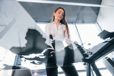 Aşağıdan bak. Beyaz elbiseli genç kadın modern ofiste kapalı bir yerde..