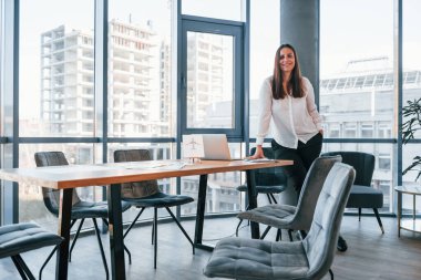 Beyaz elbiseli genç kadın modern ofiste kapalı bir yerde..