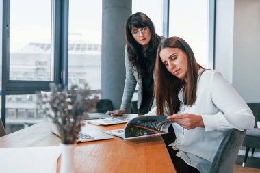 Modern ofiste resmi giyinmiş iki kadın birlikte çalışıyor..
