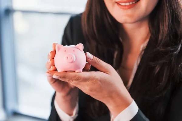 Woman Black Formal Clothes Indoors Modern Office Holds Pink Piggy — стоковое фото